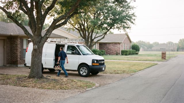 Plumber loading a work van in a north Texas driveway, a service area business with no storefront